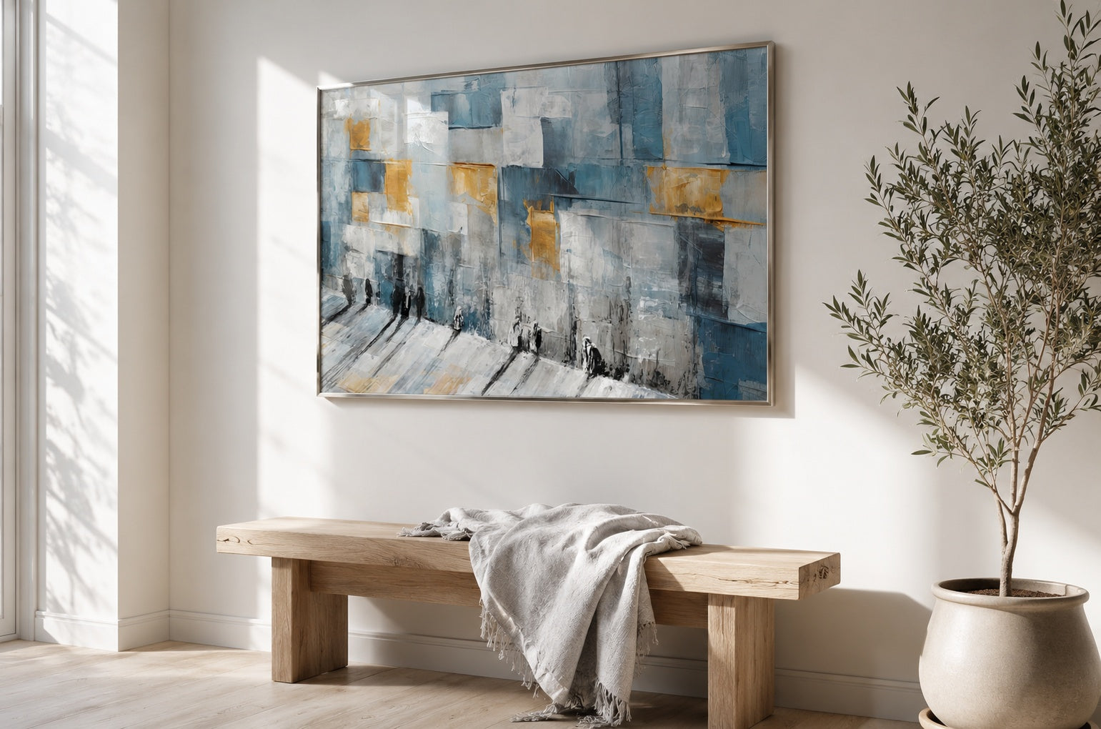 Abstract Kotel painting in blue, white, and gold tones, framed and hung above a light oak bench in a bright minimalist dining room.