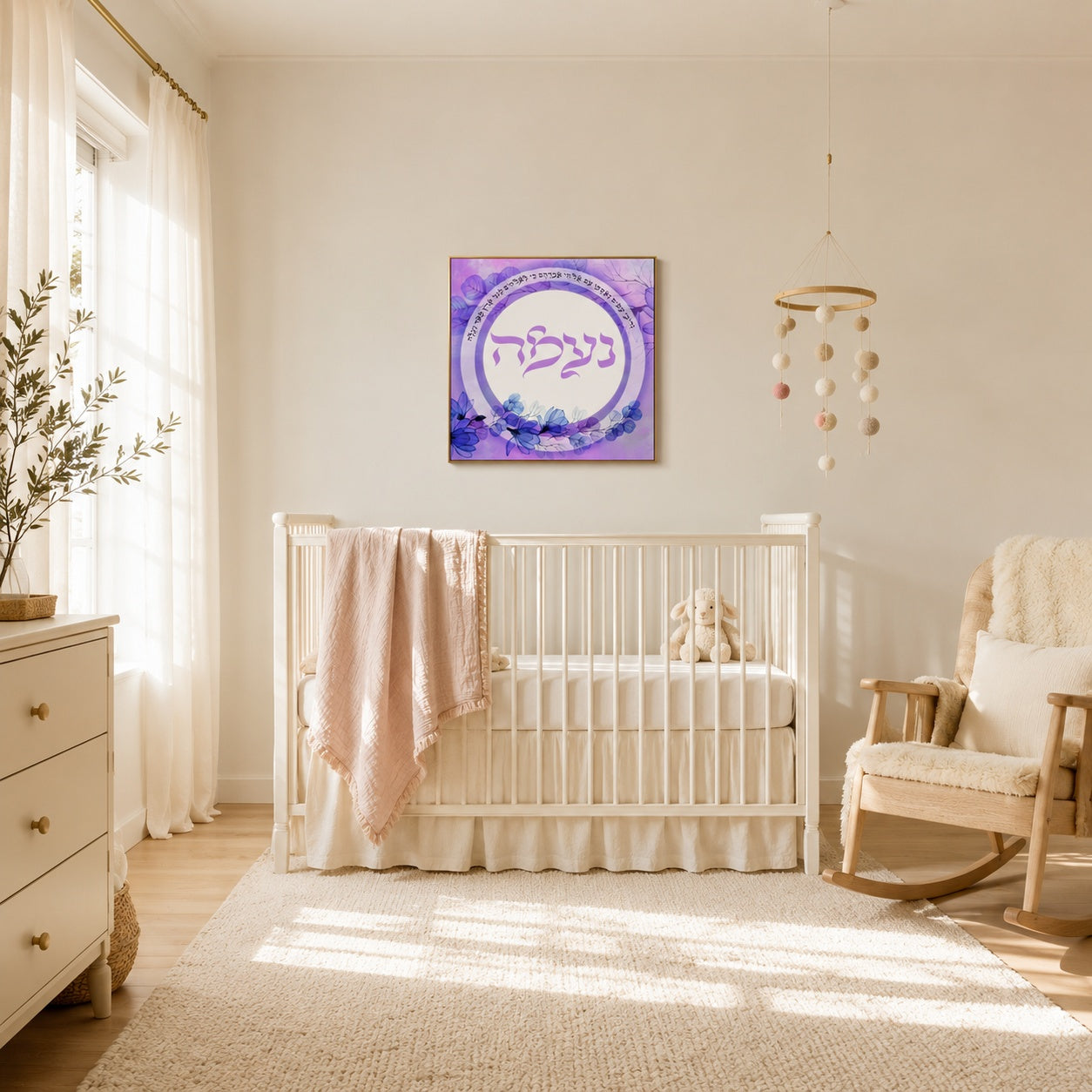 Purple watercolor Hebrew name and Torah verse wall art hung above a white crib in a sunlit cream nursery.
