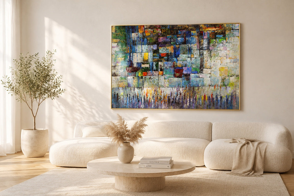 Abstract Western Wall painting with colorful Kotel stones and worshippers in brass floater frame above ivory sofa in minimalist living room.
