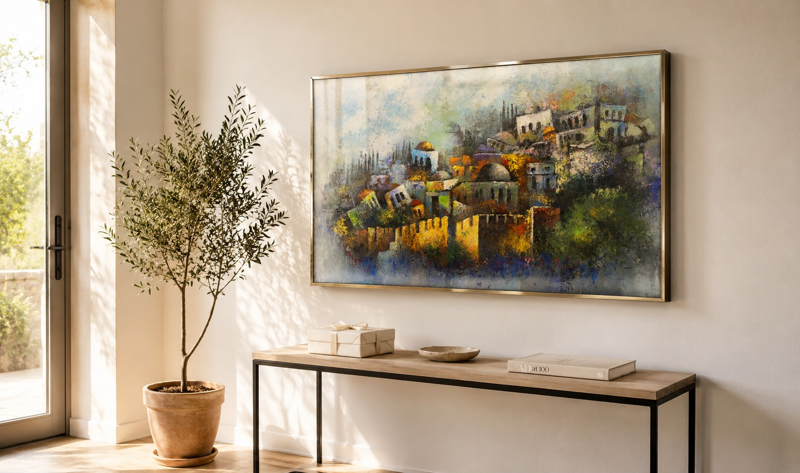 Abstract Jerusalem Old City painting in gold, green, and blue tones, brushed brass floater frame above a console in a bright minimalist living room.