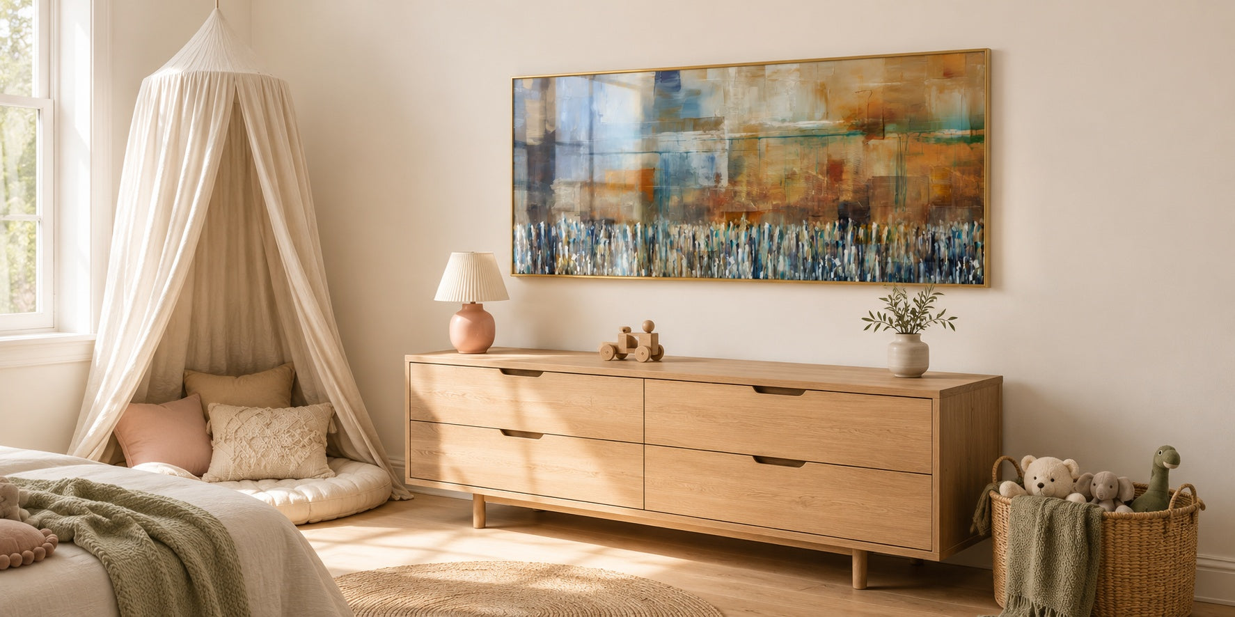 Wide abstract painting in blue and amber tones hung above a light oak dresser in a soft cream nursery with canopy.